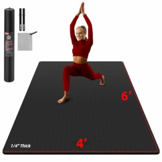 Woman practicing yoga on a large black mat with accessories.